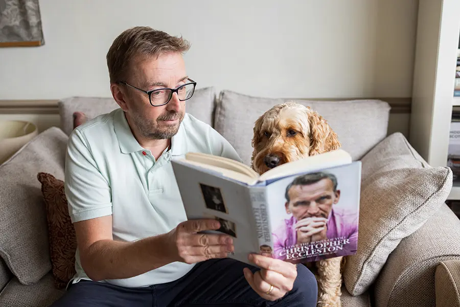 UK Ghost writer John Woodhouse sits with his dog looking at the Christopher Eccleston book that he has ghostwritten